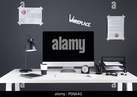 desktop computer with blank screen, business charts and office supplies at workplace Stock Photo