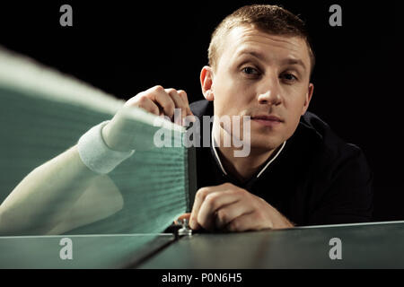 selective focus of young tennis player looking at camera isolated on black Stock Photo