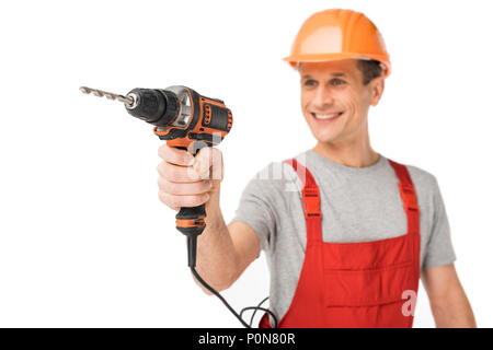 Smiling handyman in overalls holding drill isolated on white Stock Photo