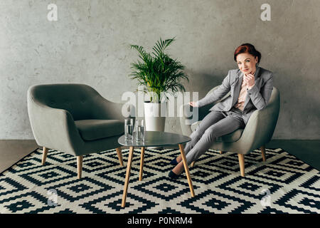 successful mature businesswoman resting on armchair in loft lobby interior Stock Photo