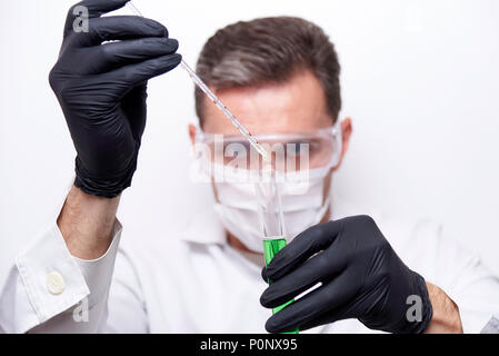 A test tube with a green liquid in the hands of a scientist chemist is isolated on a white background. The experiment is conducted by a scientist wear Stock Photo