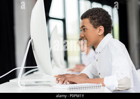 side view of african american teen boy typing on keyboard in front of ...