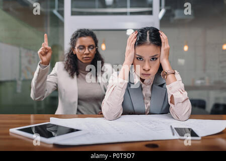 stressed multiethnic businesswomen working with documents in office Stock Photo