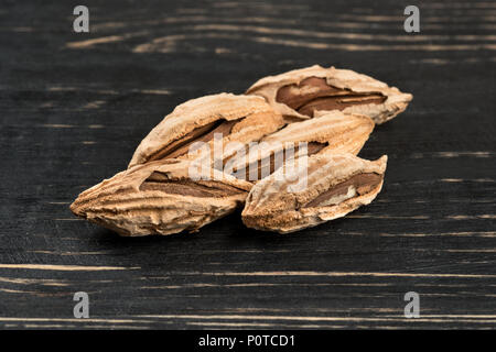 Wild uzbek inshell almonds on wooden background Stock Photo