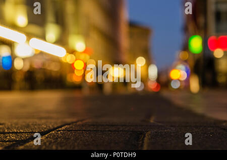 Ppedestrian road in the night city with a bright bokeh on the background.  Blurry background texture of street at night in urban city environment. Stock Photo