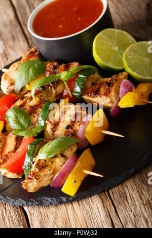 spicy grilled chicken kebabs with vegetables served with ketchup close-up on the table. vertical Stock Photo