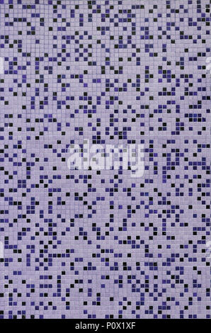The texture of the wall, decorated with a mosaic of various small square tiles. Abstract pattern of ceramic tiles on the wall Stock Photo