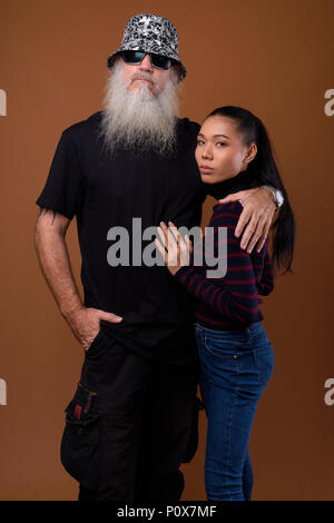 Mature bearded bald man with young Asian transgender woman Stock Photo