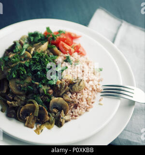 Red rice with mushrooms and cherry tomatoes. Vegan dish. European cuisine. Simple healthy lunch. Vegetarian rice dish on the white plate. Close up. To Stock Photo