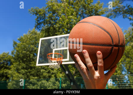 closeup male hands throwing basketball ball in target outdoors Stock Photo