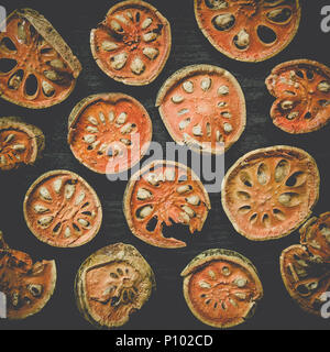 Dried herbs and dried bael fruit, Top view of bael dry on the wooden floor, Slices of bael fruit for make bael juice on the dark table. Stock Photo