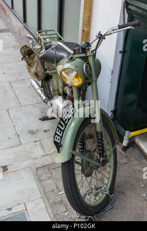a vintage military motorcycle in army  green colour parked on a pavement in daily use. Stock Photo