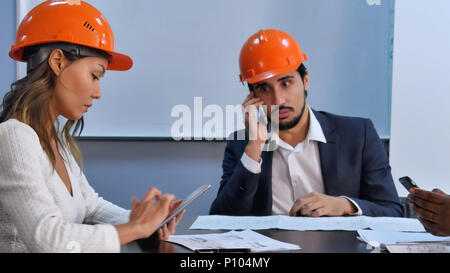 Executive team using smartphone and digital tablet sitting in office Stock Photo