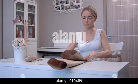 Young woman folding and cutting wrapping paper Stock Photo