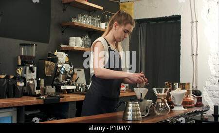 Barista making hand brewed coffee, adding grinded coffee and pouring hot water Stock Photo