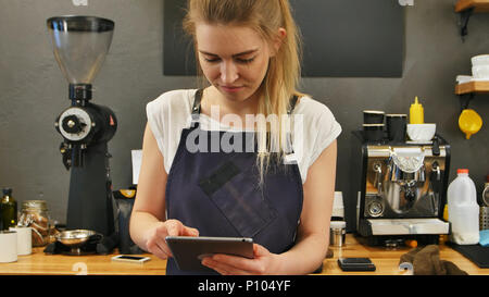 Smiling and cheerful barista using digital tablet for work Stock Photo