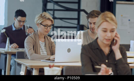 Busy design office with workers at desks Stock Photo