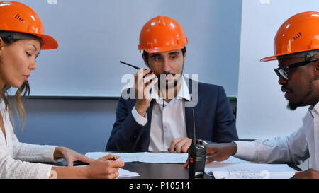 Multiracial construction engineers on meeting in bright modern office Stock Photo