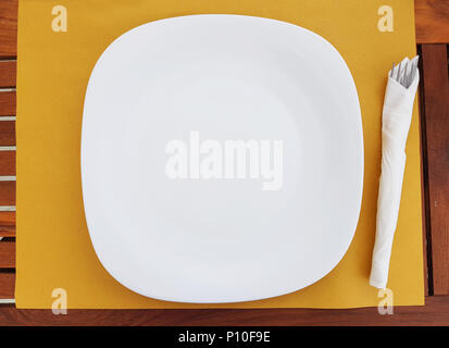 Top view of empty white plate, white dish with napkins set on the table in restaurant outdoor. Stock Photo