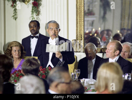 Emperor Hirohito reads a toast at the State Dinner held in his honor, and that of Empress Nagako’s, during their first official State Visit to the United States.  Also shown are First Lady Betty Ford, a waiter, an interpreter, and President Gerald R. Ford.  October 2, 1975. Stock Photo