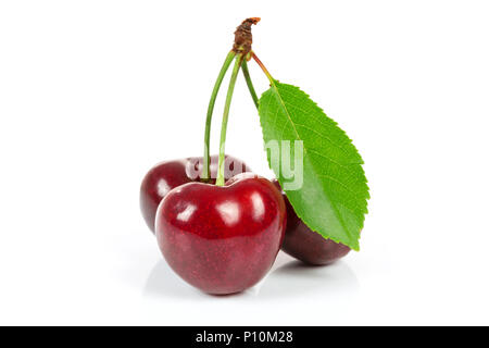 Three ripe cherries with leaf isolated on a white background in close-up Stock Photo