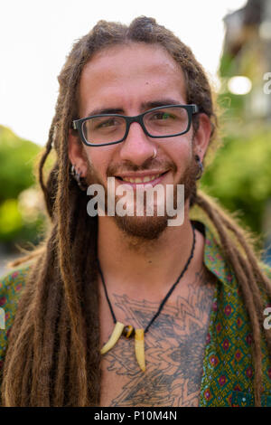 Young handsome Hispanic tourist man with dreadlocks in the stree