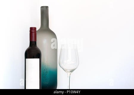 Wine bottle with empty label, wineglass and decorative frosted glass bottle on white background with copy space Stock Photo
