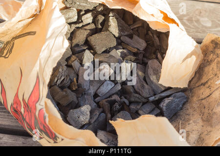 Black glossy coal for bonfire and bbq from supermarket inside a craft brown paper bag. Stock Photo