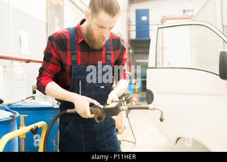 Car Mechanic Using Oil Gun Stock Photo