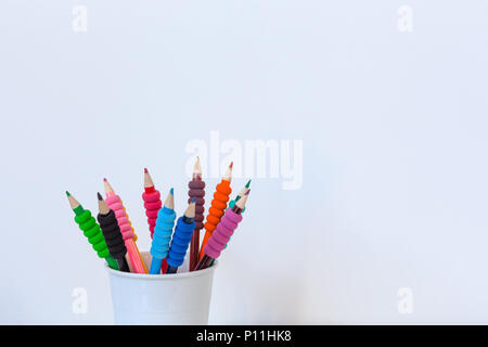 Colored pencils in white cup against white wall with copy space Stock Photo
