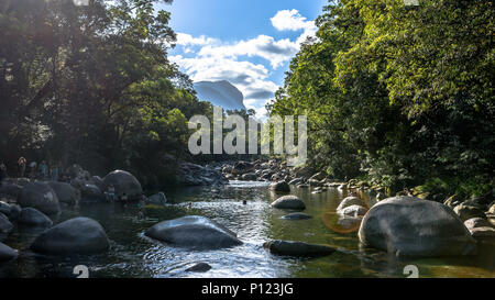Tourists looking at and swimming in the Mossman River in the Mossman Gorge in Far North Queensland, with lens flare Stock Photo