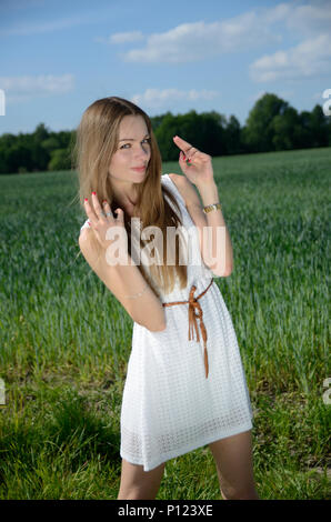 Petite woman walking in the grain field, wearing white dress