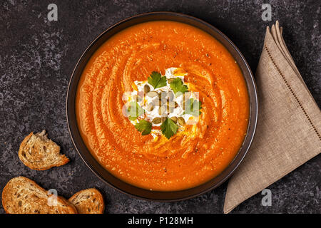 Pumpkin and carrot soup with cream, seeds and parsley. Top view. Stock Photo