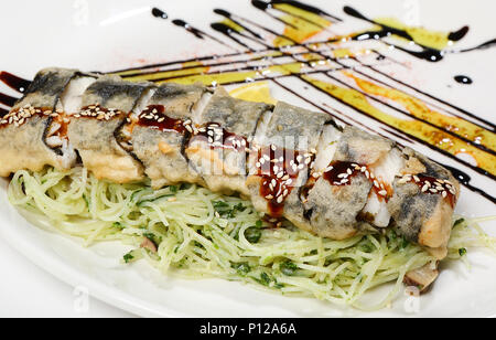 Sea bass fillet in tempura on a pad of rice noodles with shitaki, spinach, cream and Unagi sauce. Stock Photo