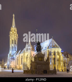 The equestrian statue of Saint Stephen looking at the Matthias Church with snow Stock Photo