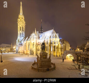 The equestrian statue of Saint Stephen looking at the Matthias Church with snow Stock Photo