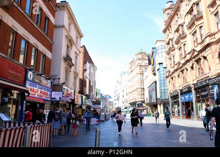 Leicester Square / St Martin's Court area of London, UK showing people walking around in the sunshine.  Theatre and tourism area. Stock Photo