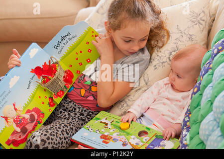 Six year old girl reading to her baby cousin Stock Photo