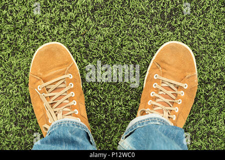 Man in leather shoes and jeans stands on fresh green grass, top view Stock Photo