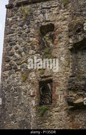 Invergarry, Scotland - June 11, 2012: Closeup of Tall dark-brown ruined wall with window openings of castle Invergarry. Stock Photo