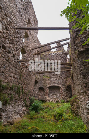 Invergarry, Scotland - June 11, 2012: Tall dark-brown ruined inside walls with wooden studs to support them at castle Invergarry. Weeds have conquered Stock Photo