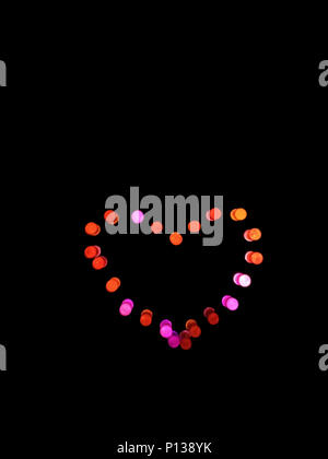 Backlit colored pegs in the shape of a heart, created on a children's game. Stock Photo
