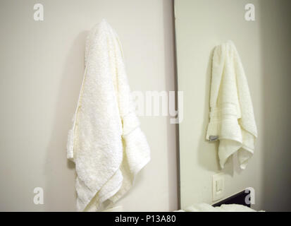 White towel hanging in bathroom on the wall across from mirror Stock Photo