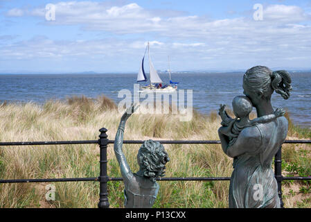 White yacht sails past the statue''Welcome home'' sculptured by Anita Lafford on the Promenade,Fleetwood,Lancashire,UK Stock Photo