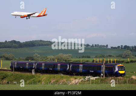 An easyjet plane landing at Edinburgh airport flies over a scotrail train making its way to Edinburgh Waverley station Stock Photo
