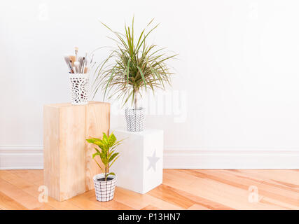 Paintbrushes and houseplants in hand-painted ceramic pots. Gold Dust Croton plant and Dracaena marginata tricolor, or Madagascar dragon tree. Stock Photo
