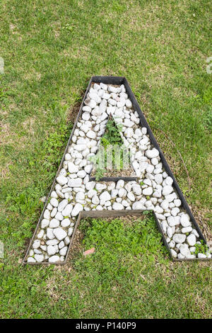 Letter A built from white stones on green grass as seen from high above Stock Photo