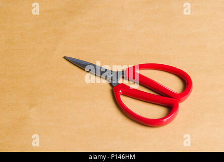 red scissors on brown background Stock Photo