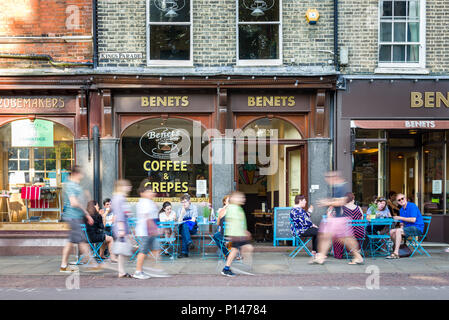 People sitting outside Benets coffee shop as well as walking past on the pavement, Kings Parade, Cambridge, UK Stock Photo