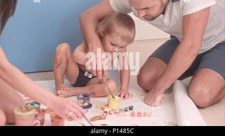 Young father teaching his kid boy how to paint Stock Photo